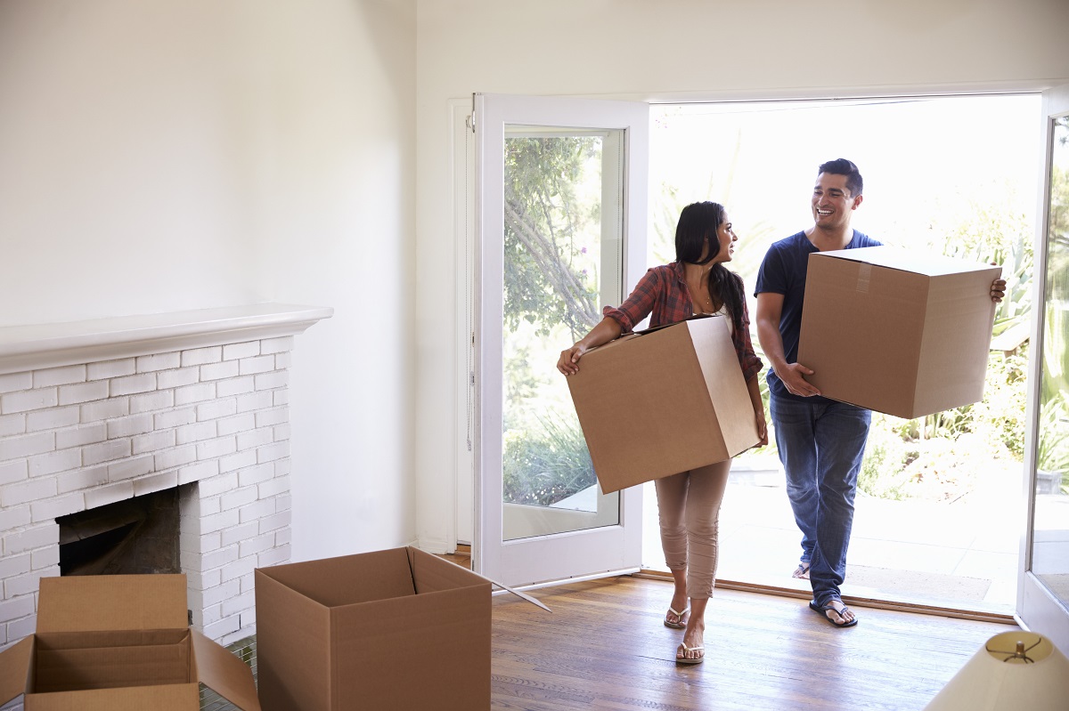 Um casal carregando caixas para nova casa no dia da sua mudança